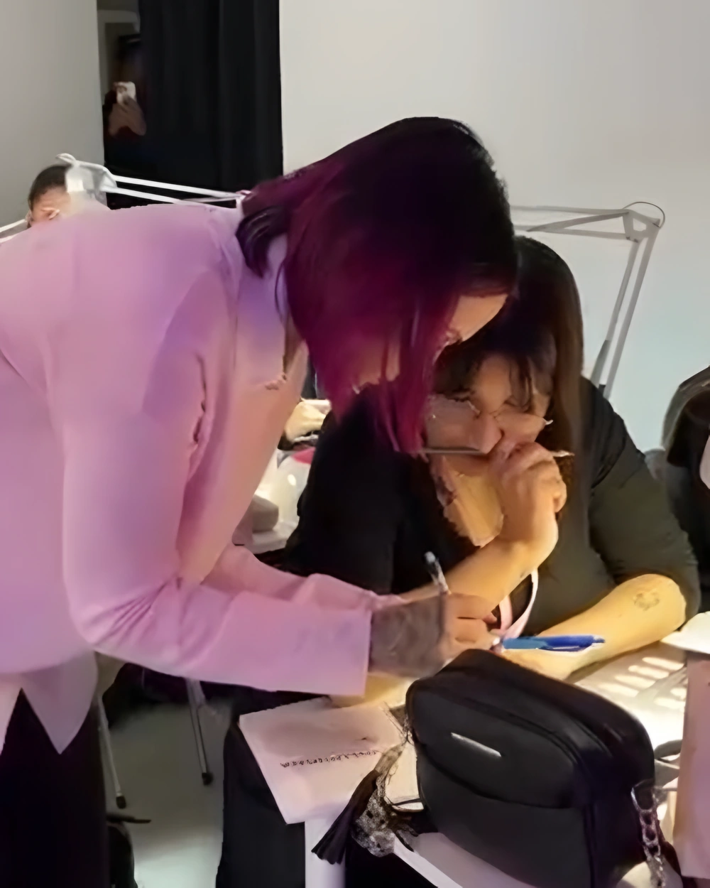Laura corrigiendo de cerca el trabajo de una alumna